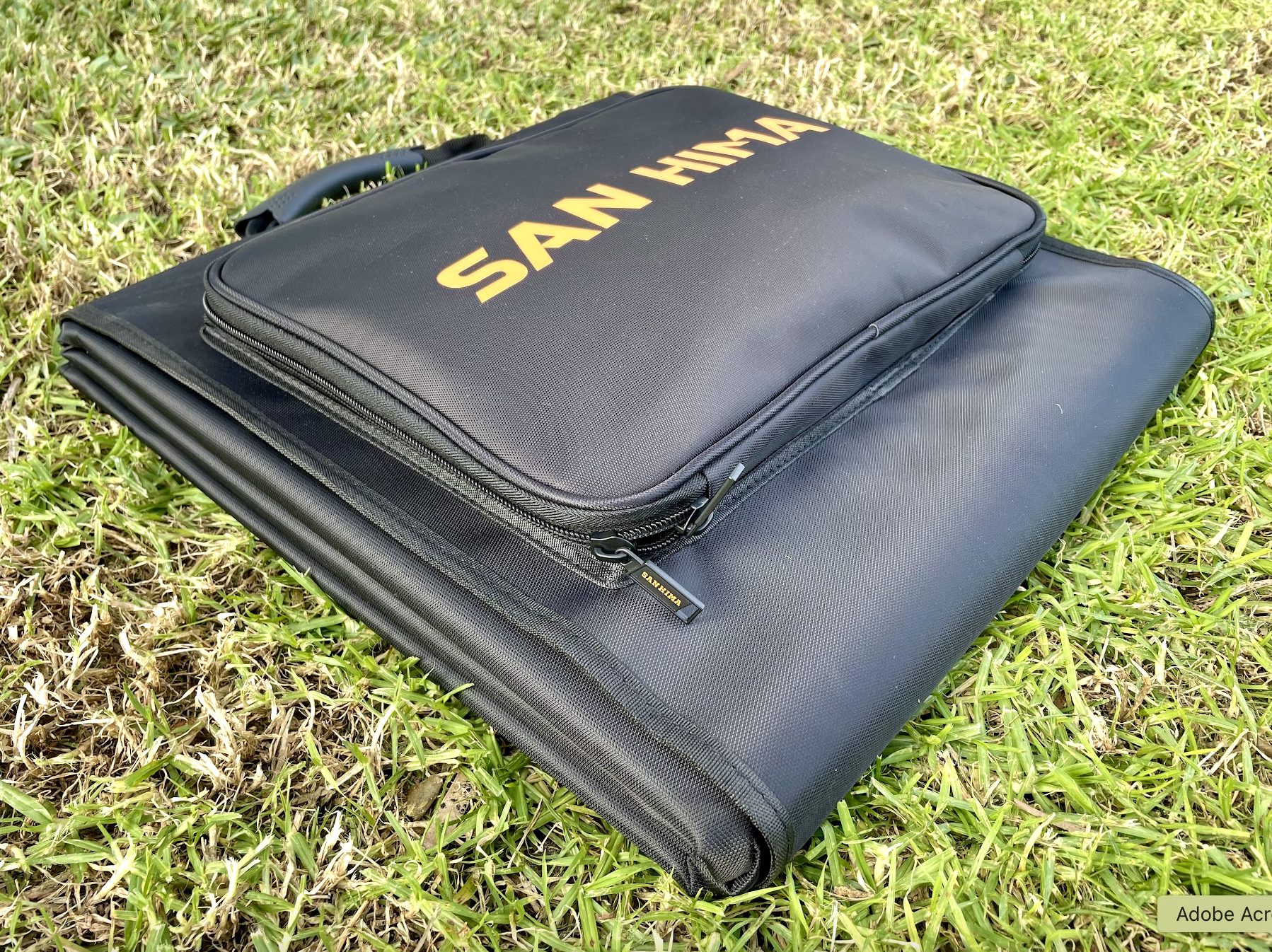 Rugged reinforced carry case of the San Hima 160W solar blanket in grass