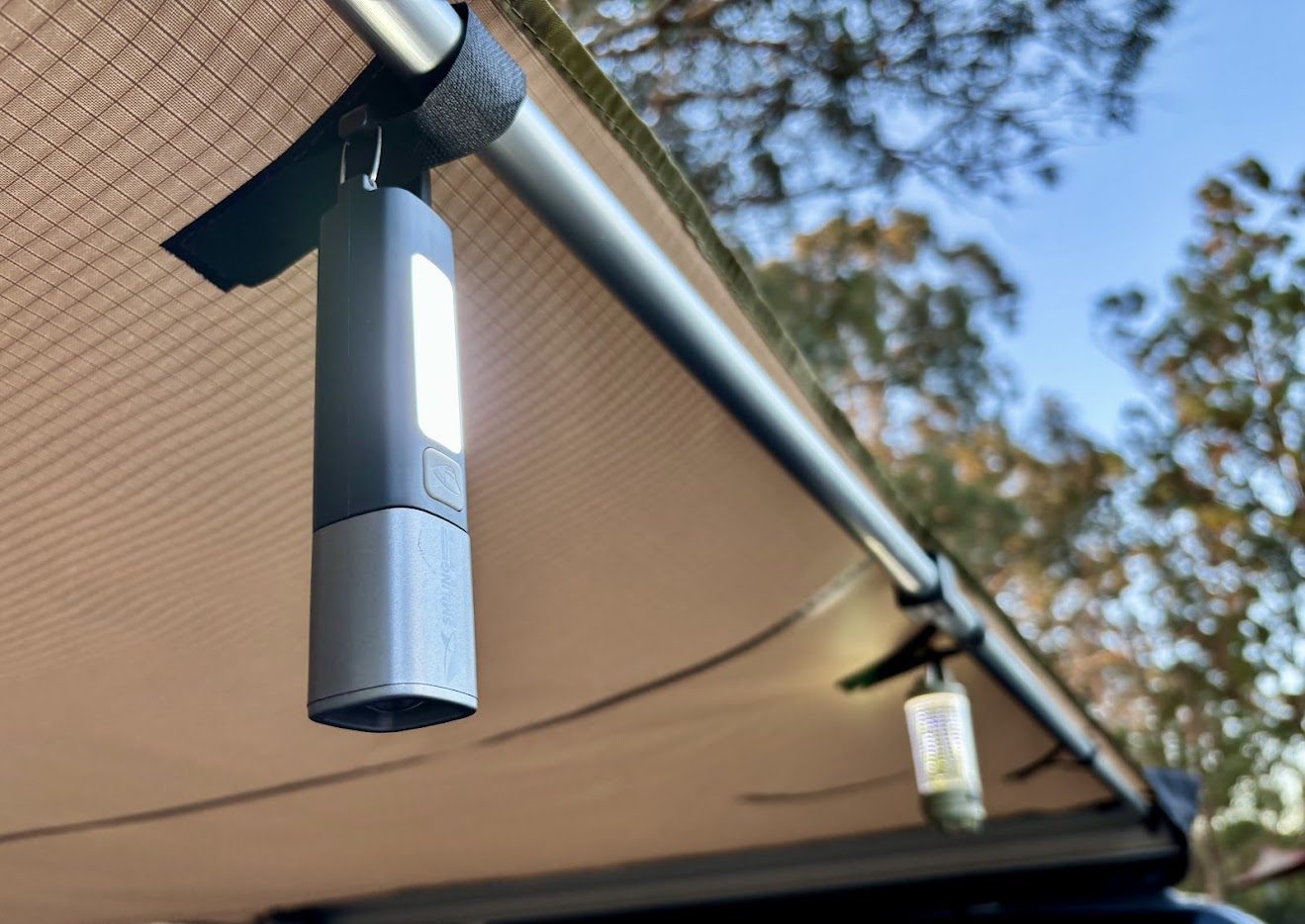 Black Smiling Shark camping torch in floodlight mode hanging under XTM awning