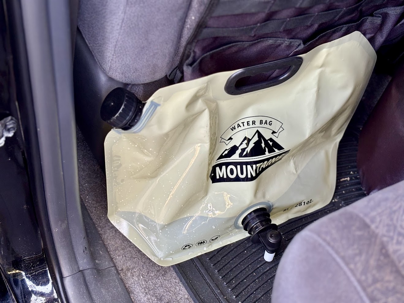 Filled up camping water bag​ stored behind the front seat