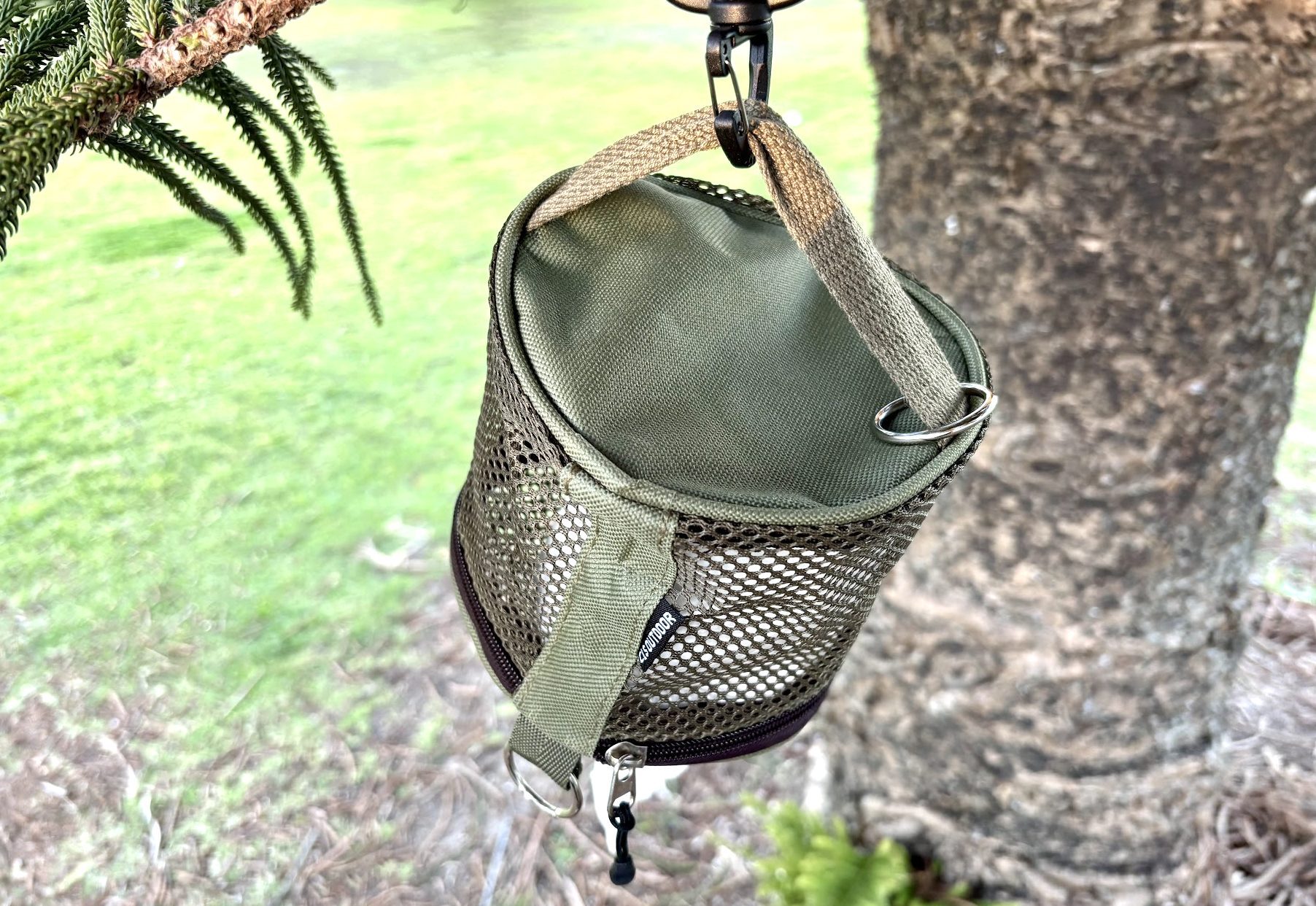 Hanging the green mesh toilet paper holder from a tree branch
