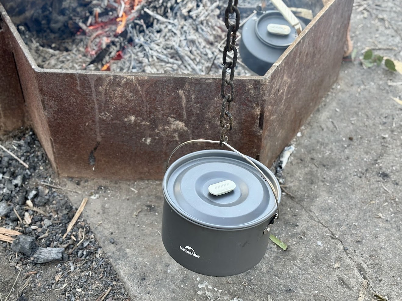 The largest pot of the Naturehike camping pot set comes with a clever handle to carry it or hang it over a campfire