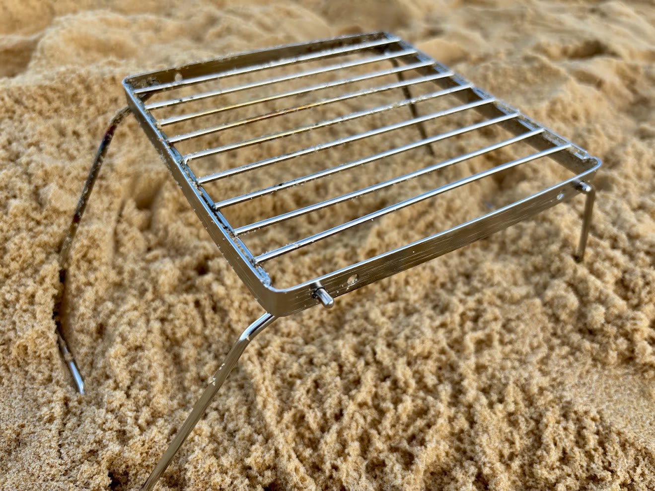The legs of this compact folding campfire grill​ fold out to about 13cm height and feel very stable